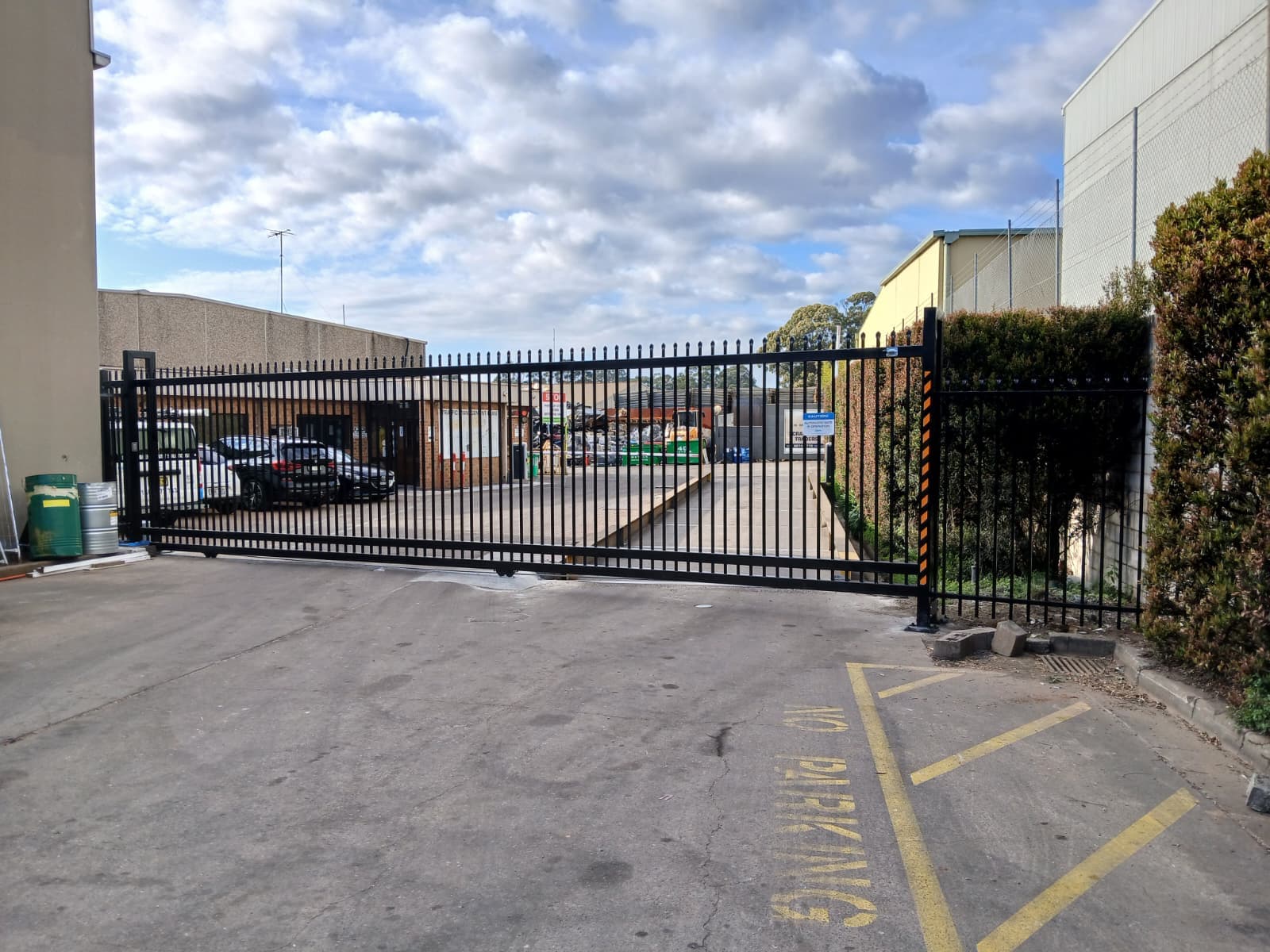 Completed black commercial automatic sliding gate across a facility driveway.