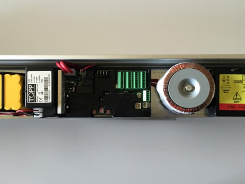 Internal view of an automatic door motor system, showing the TOPP control unit, wiring, connectors, and drive mechanism for sliding door automation.