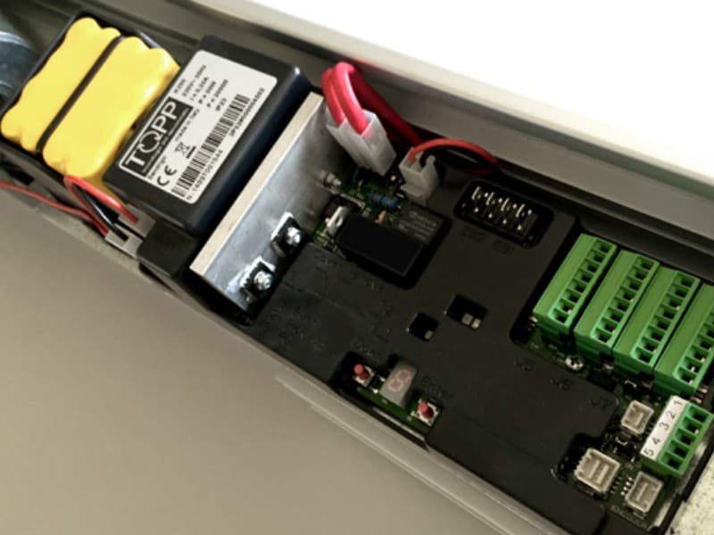 Internal view of a K280 automatic sliding door control unit, showing battery backup, wiring connections, control board, and green terminal blocks for system integration.