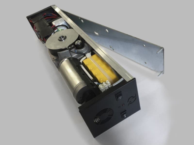 Internal view of an automatic swing door operator with its cover removed, revealing motor, control electronics, battery pack, and drive mechanism components.