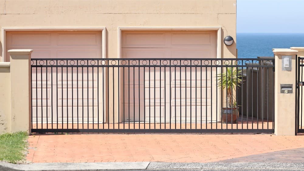 Modern black residential sliding gate securing a double driveway with garage access.