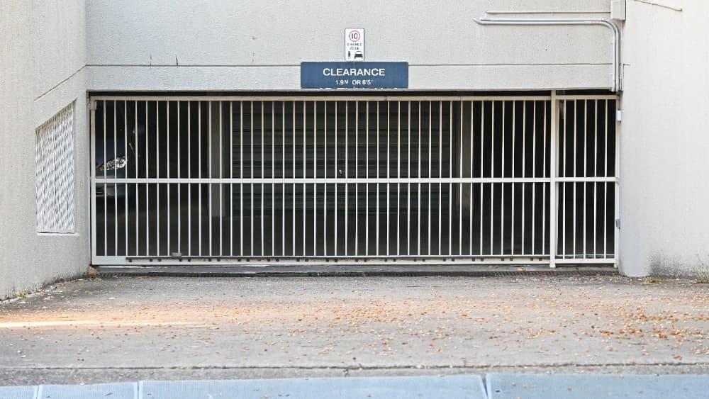 White sliding gate at underground car park entry with clearance signage.