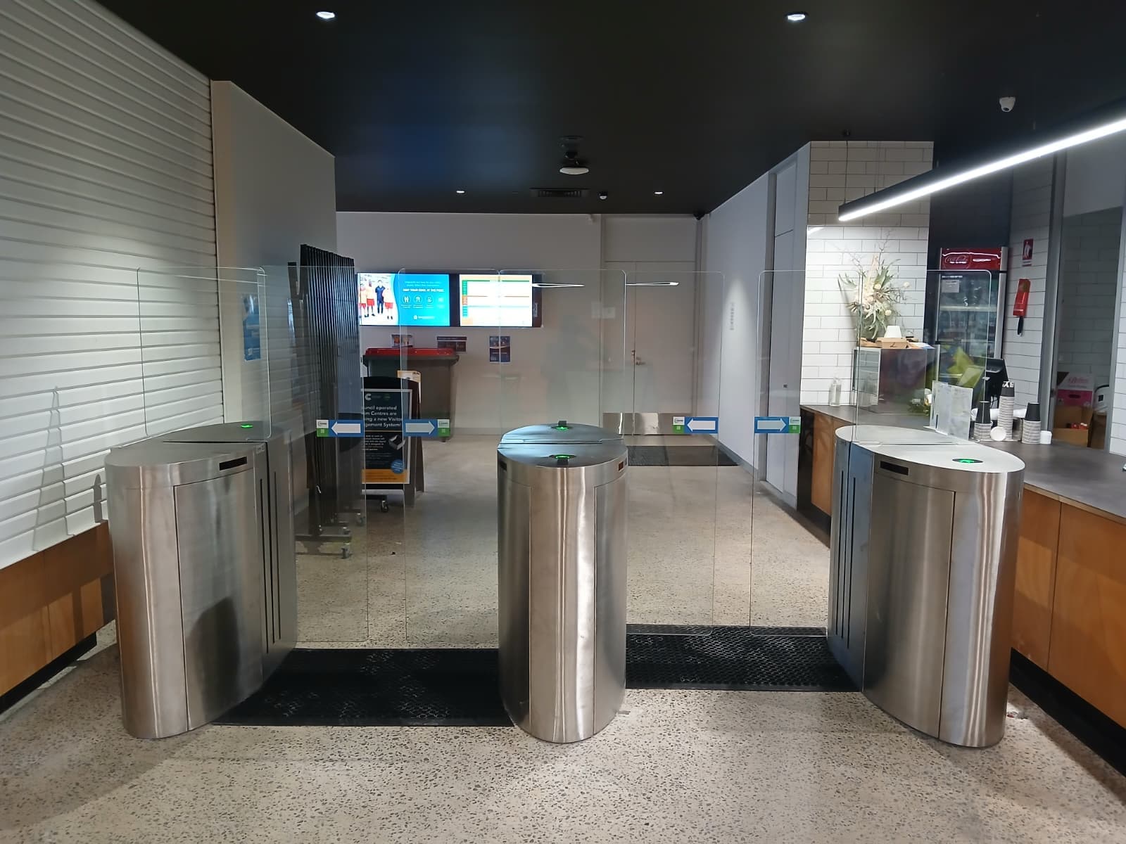 Three stainless speed gates controlling pedestrian access in a commercial lobby.